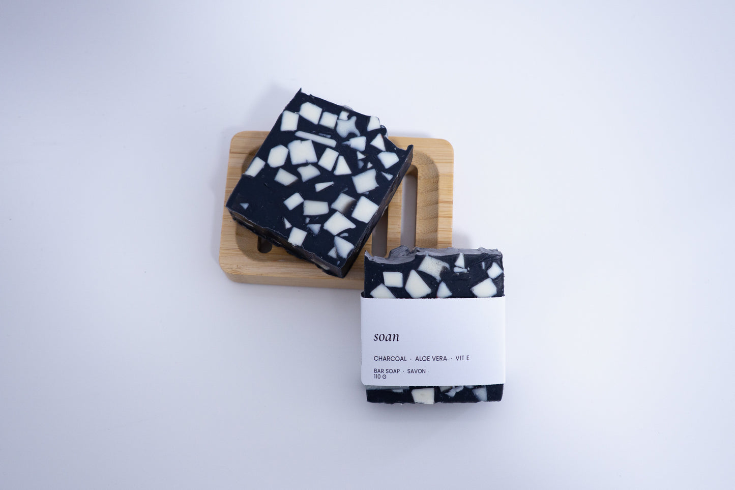 Black and white patterned soap bars on a wooden block with a white background