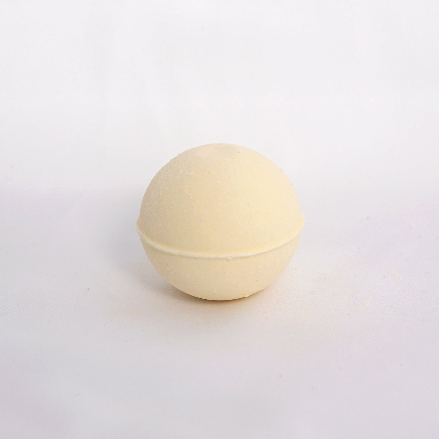 Citrus-scented bath bomb on a neutral surface, crafted with essential oils and skin-softening ingredients for an uplifting soak
