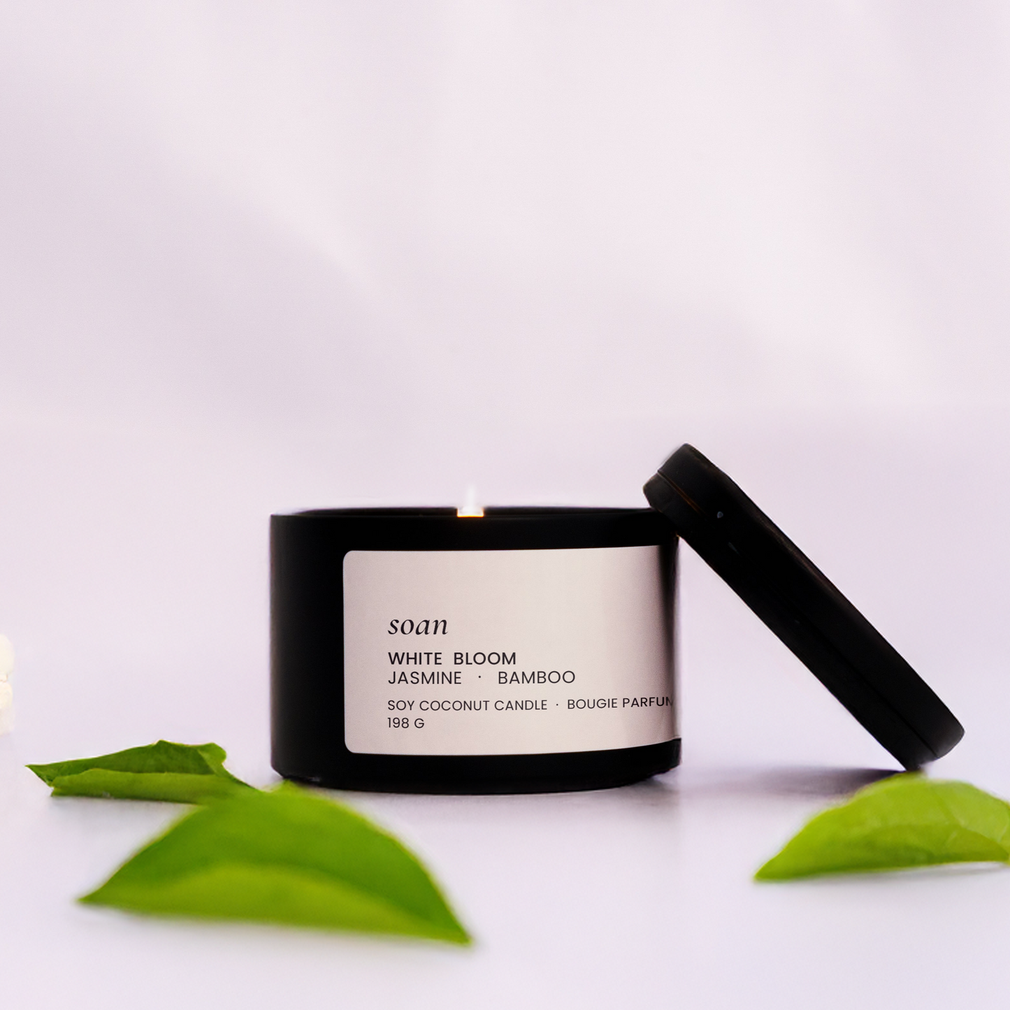 Black candle with a label on a white background with green leaves