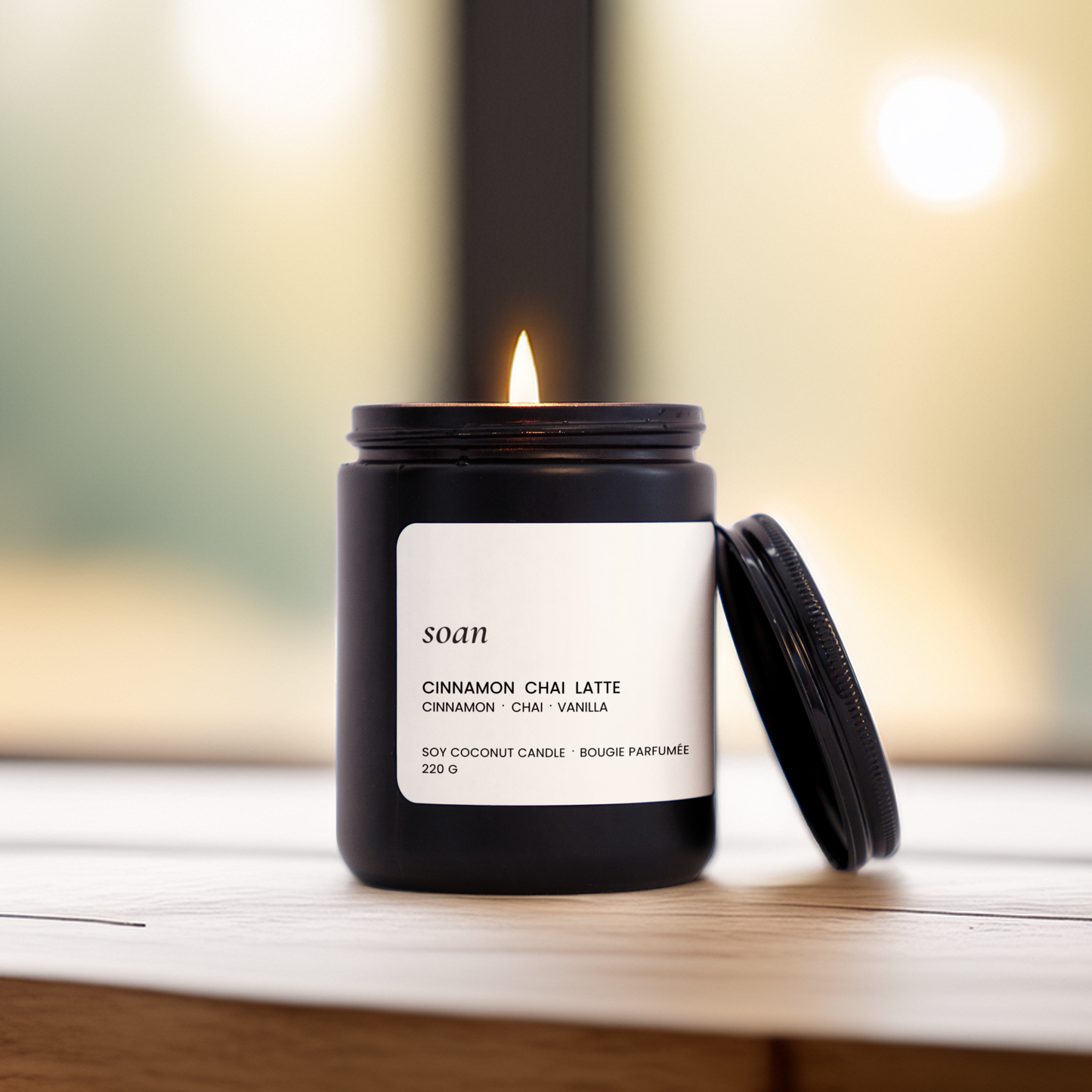 Lit Cinnamon Chai Latte candle on a wood surface, evoking warm cinnamon, creamy chai tea, and vanilla in a calming ritual setting
