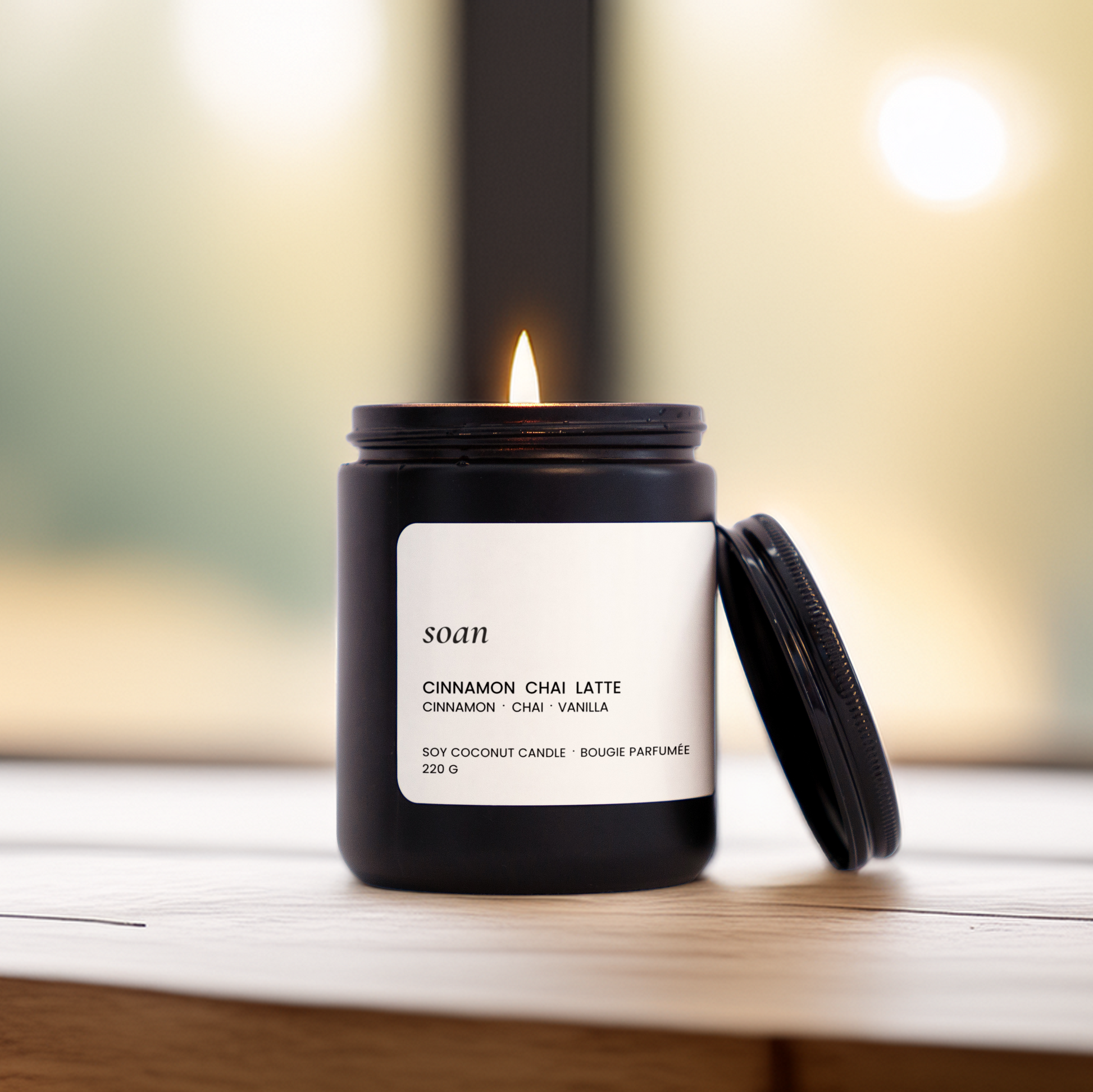 Lit Cinnamon Chai Latte candle on a wood surface, evoking warm cinnamon, creamy chai tea, and vanilla in a calming ritual setting