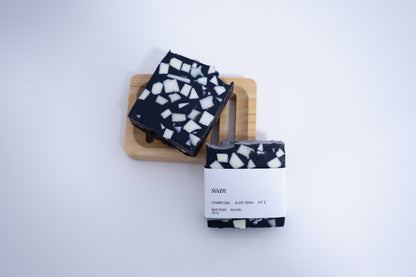 Black and white patterned soap bars on a wooden block with a white background