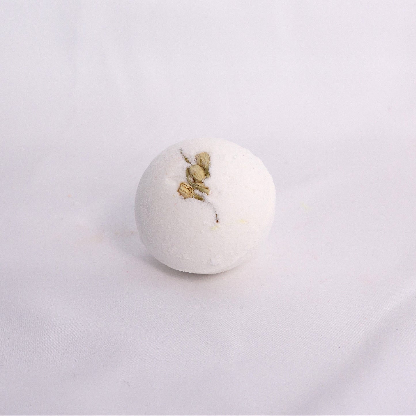 Close-up of Jasmine bath bomb on a clean surface, crafted with milk powder, shea butter, and avocado oil for soft hydration