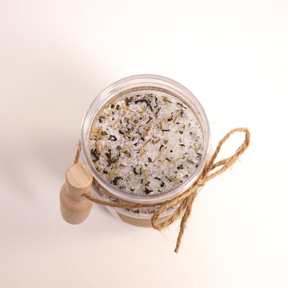 Jar of bath salts with a wooden scoop on a light background
