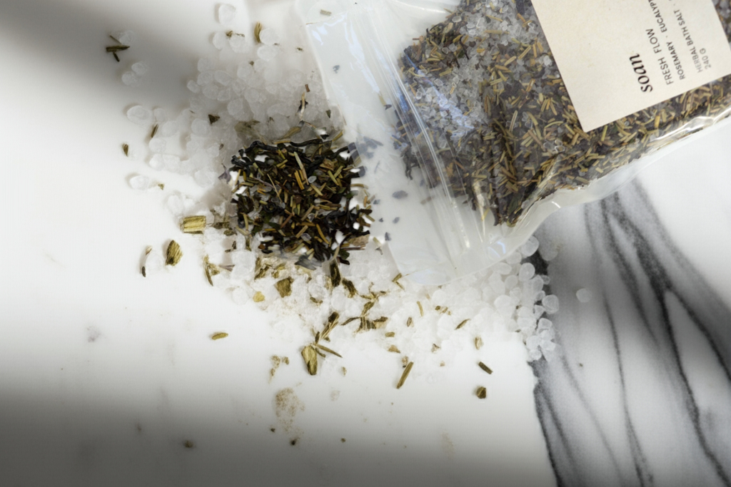 Herbal tea bath salt packaging with loose tea leaves and bath salts on a marble surface