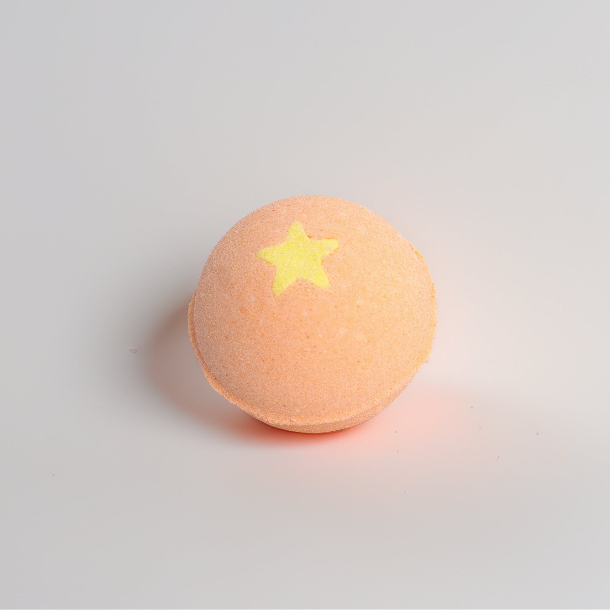Orange bathbomb with a yellow star on a light gray background