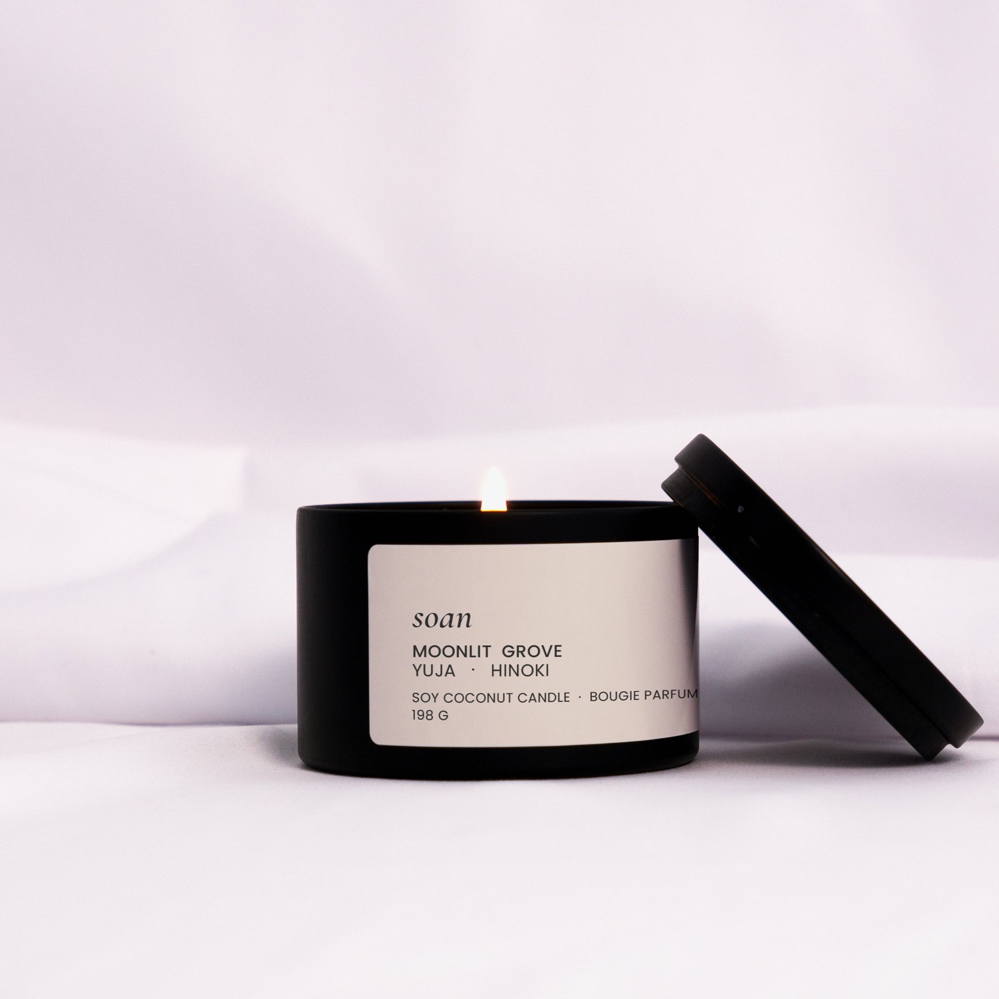 Moonlit Grove candle styled in a dim, calming setting, evoking a cool forest at dusk with floral-woody aroma
