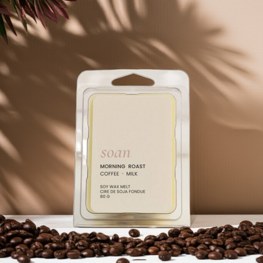 Scented wax melt packaging with coffee beans and a plant on a wooden surface