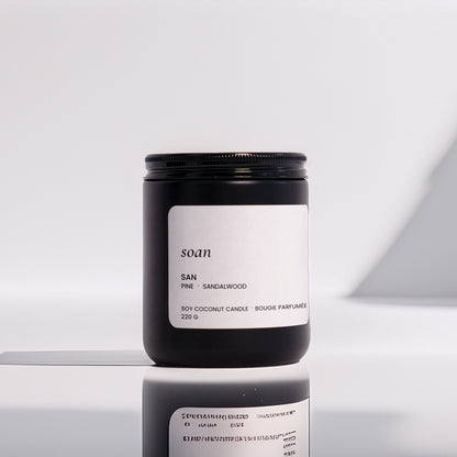 Candle jar with 'soan' branding on a reflective surface