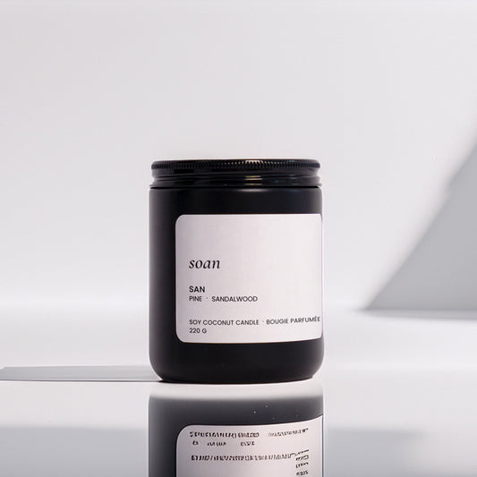 Candle jar with 'soan' branding on a reflective surface