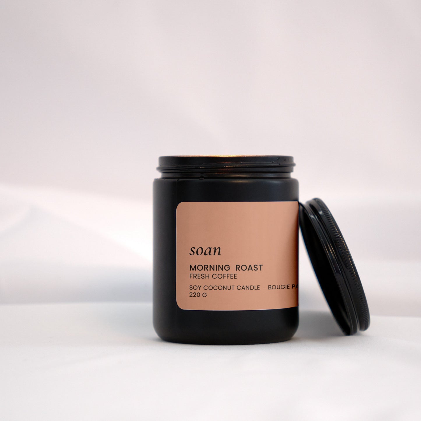 Warm-lit Morning Roast candle on a wood tray, evoking notes of brewed coffee, vanilla, and toasted hazelnut