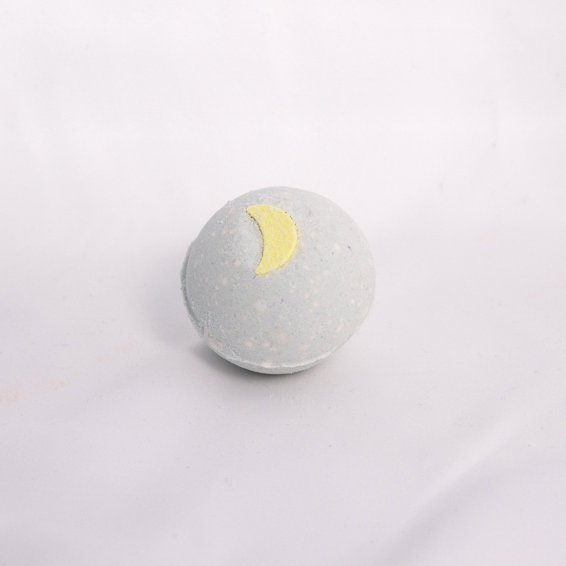 Fizzing pine patchouli bath bomb in water, releasing earthy bubbles with notes of fresh pine aromatherapy bath