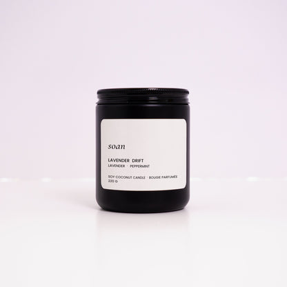 Black candle jar with a white label on a light purple background