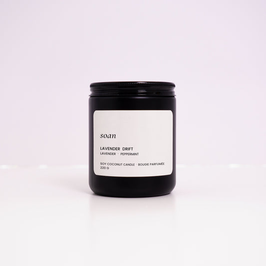 Black candle jar with a white label on a light purple background