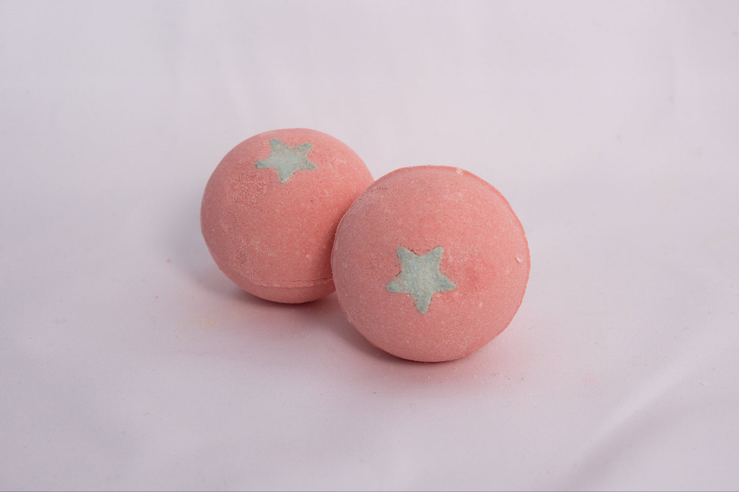Fizzing Fuji Apple bath bomb in water, releasing creamy bubbles and a sweet, crisp apple scent