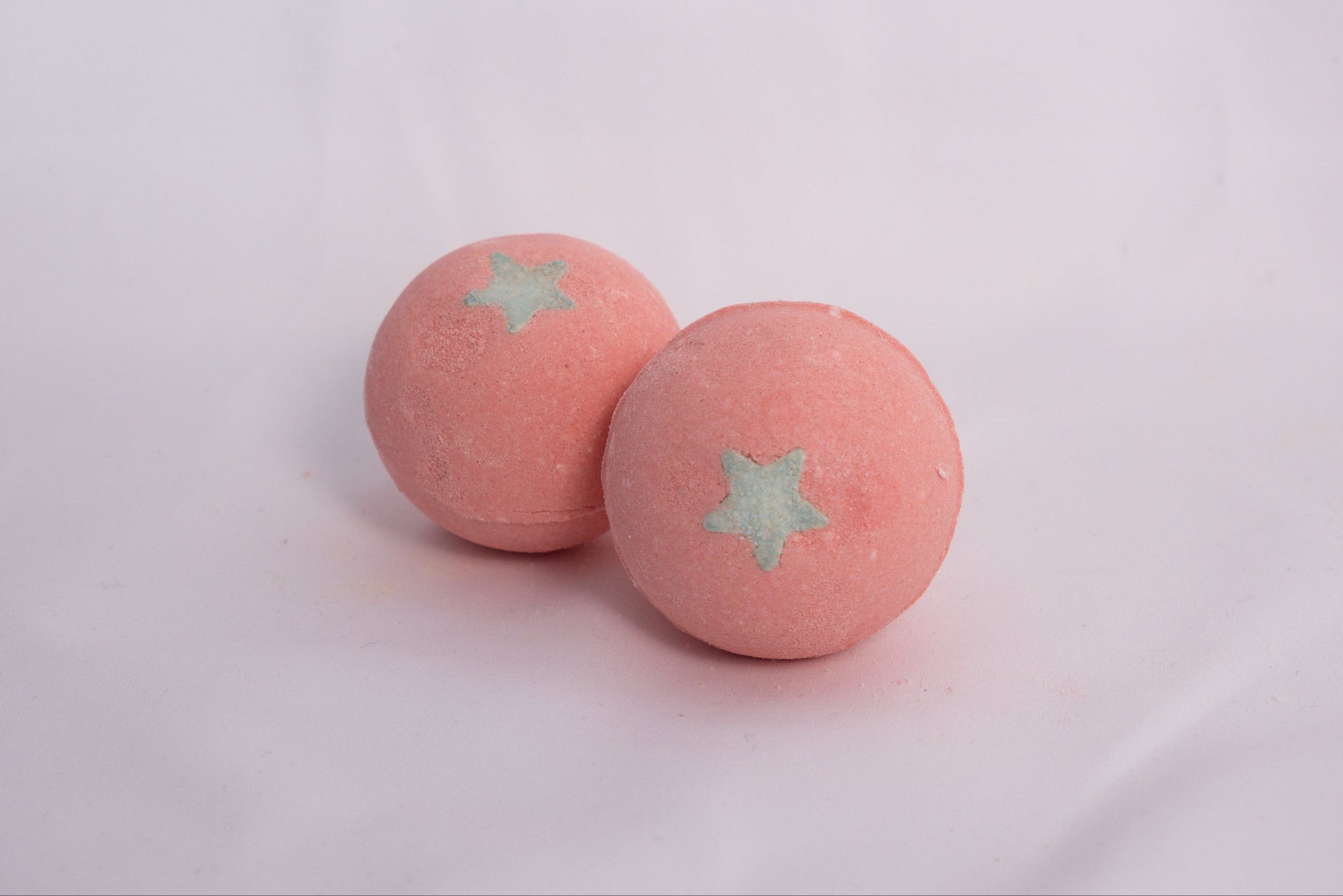 Fizzing Fuji Apple bath bomb in water, releasing creamy bubbles and a sweet, crisp apple scent