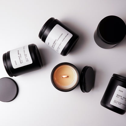 Black candles with white labels on a light gray background