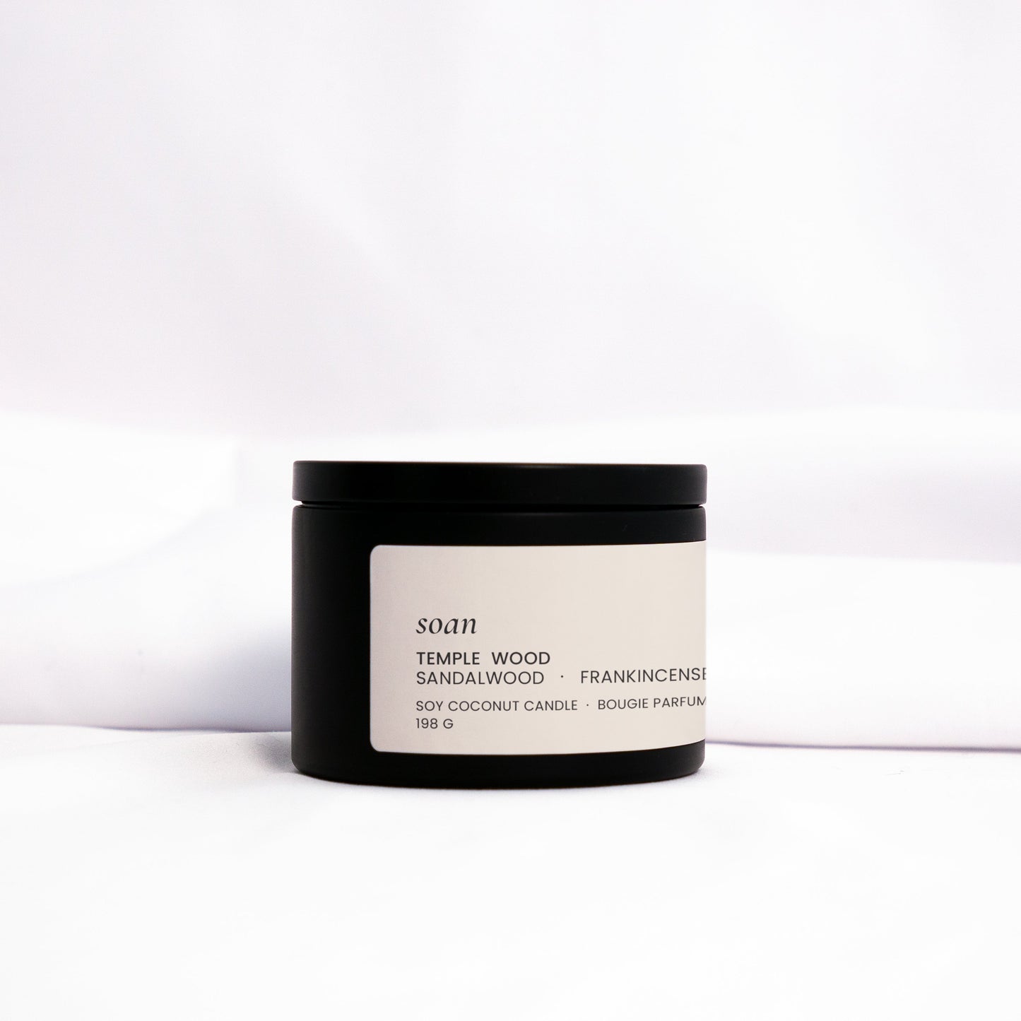 Small batch Temple Wood candle in metal tin, styled with warm tones for meditative, earthy ambiance