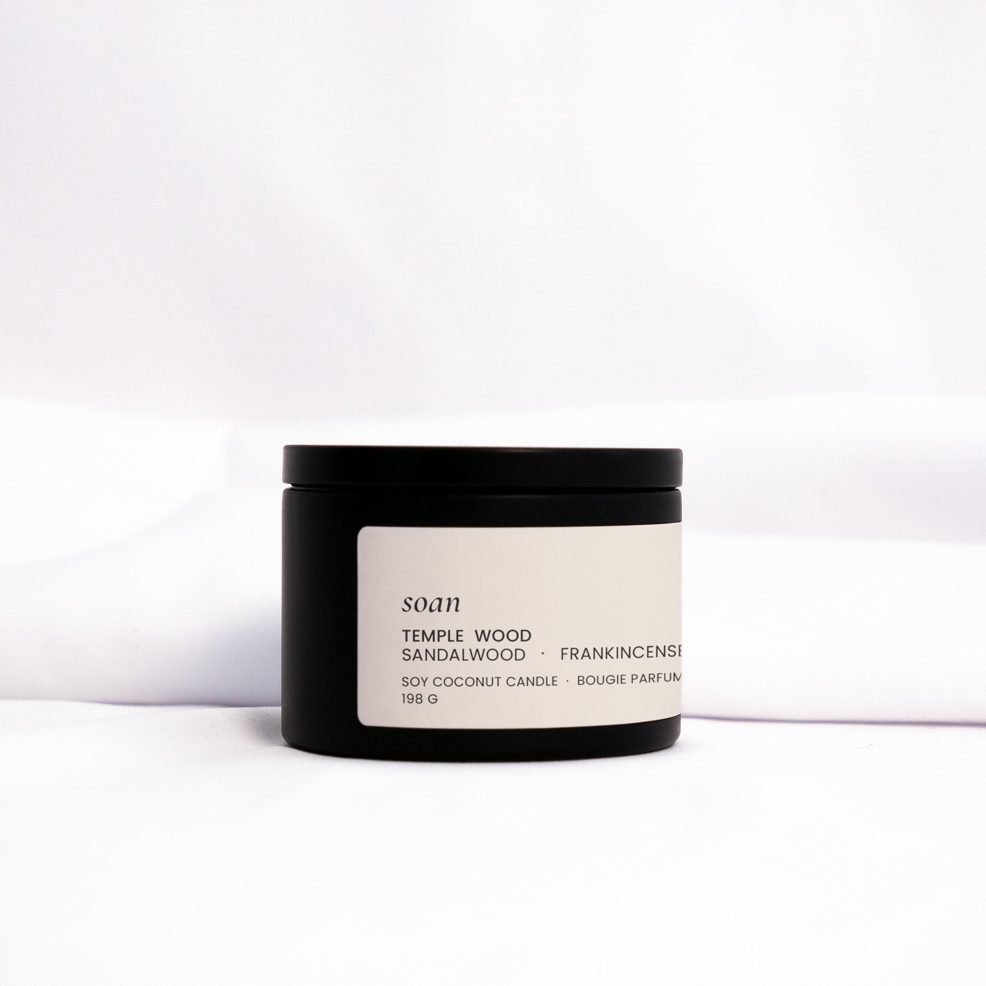 Small batch Temple Wood candle in metal tin, styled with warm tones for meditative, earthy ambiance