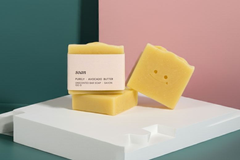 Two yellow soap bars on a white platform with a green and pink background