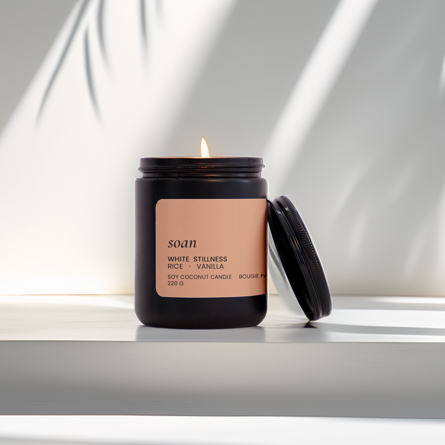 Candle with a pink label on a white surface with a light background