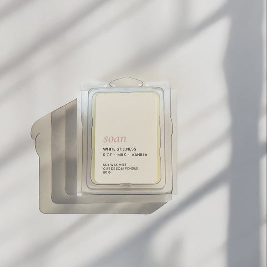 Candle with a label on a white surface with shadow patterns