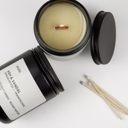 Candle with open lid, matches, and black container on a white background