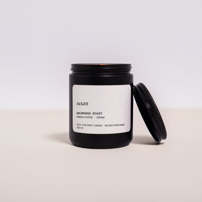 Black candle jar with a white label on a light beige surface