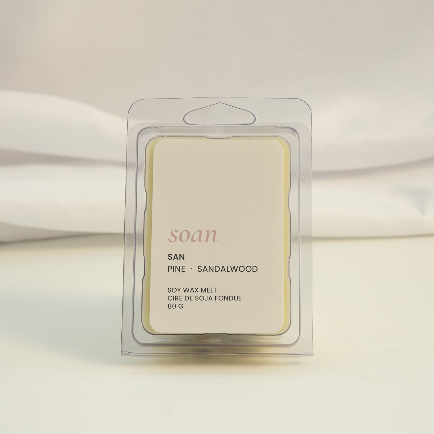 Wax melt packaging labeled 'soan' on a white fabric background