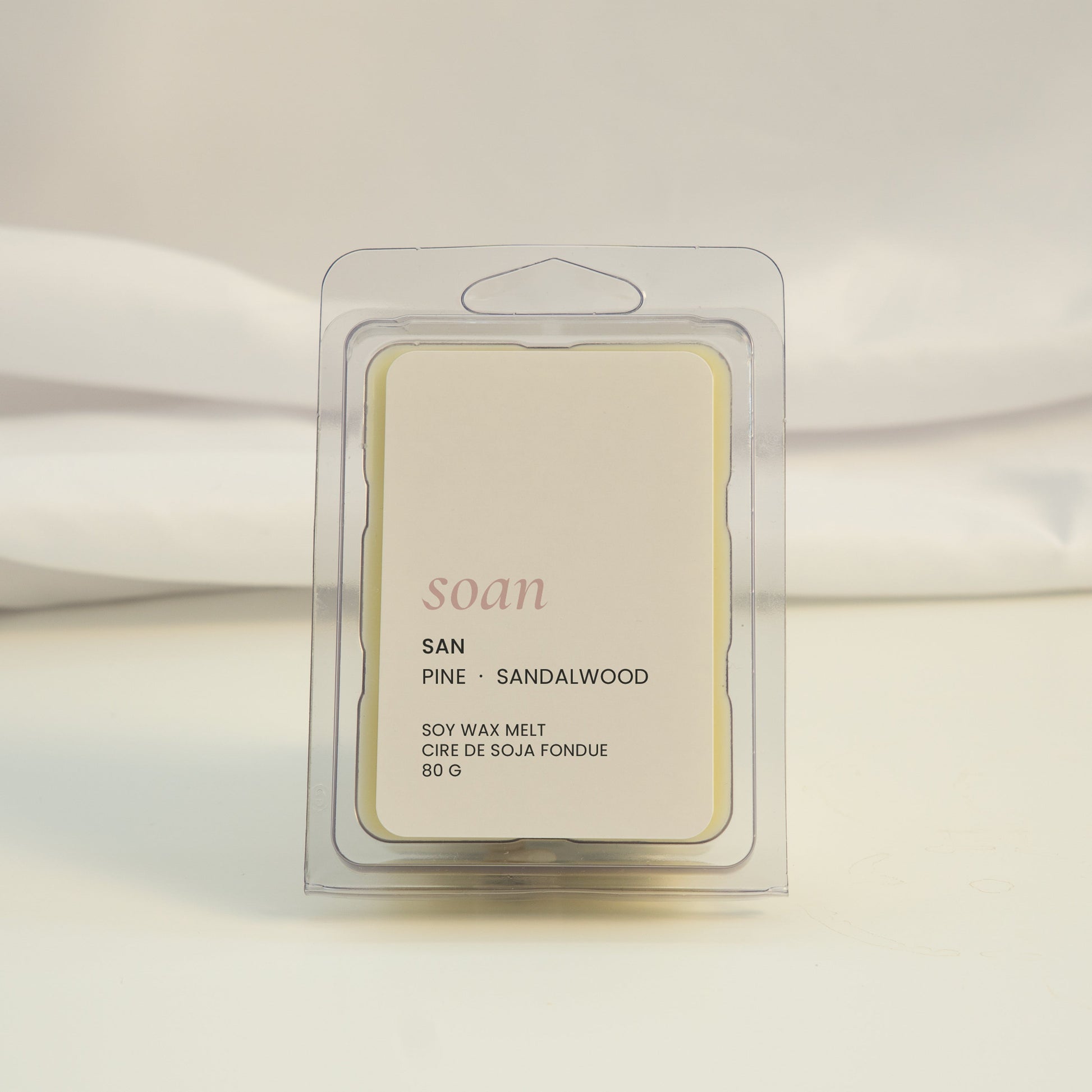 Wax melt packaging labeled 'soan' on a white fabric background