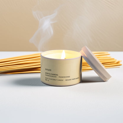 A lit candle with reed diffusers on a neutral background