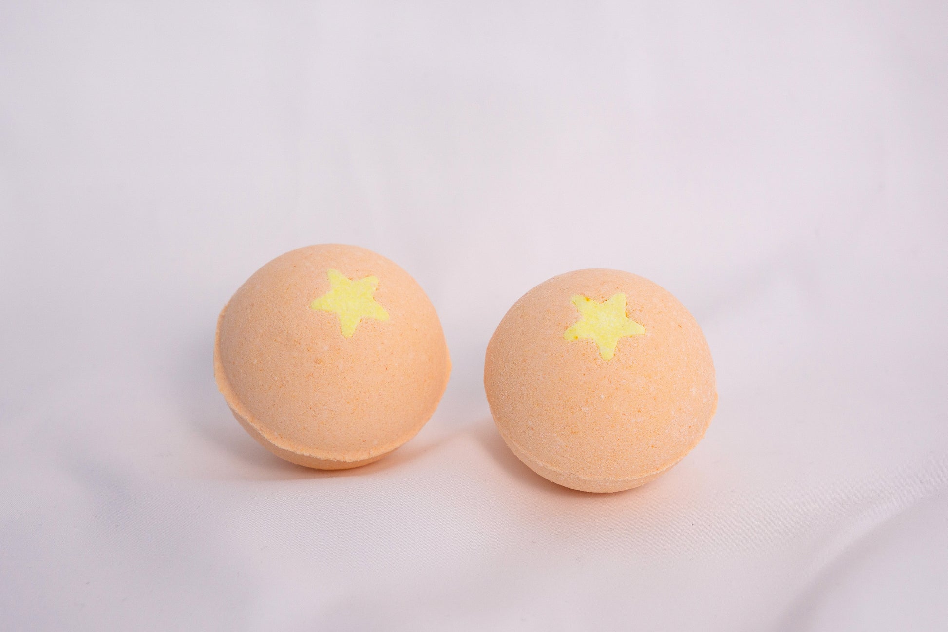 Fizzing Mango bath bomb in water, releasing soft bubbles and a vibrant, fruity aroma for a relaxing self-care ritual