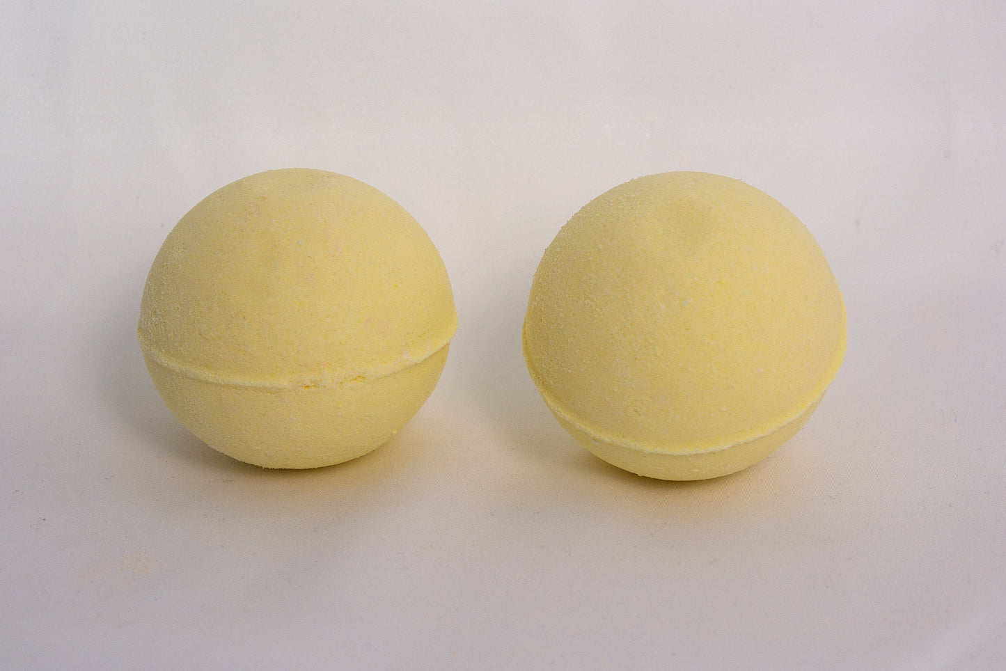 Citrus-scented bath bomb on a neutral surface, crafted with essential oils and skin-softening ingredients for an uplifting soak