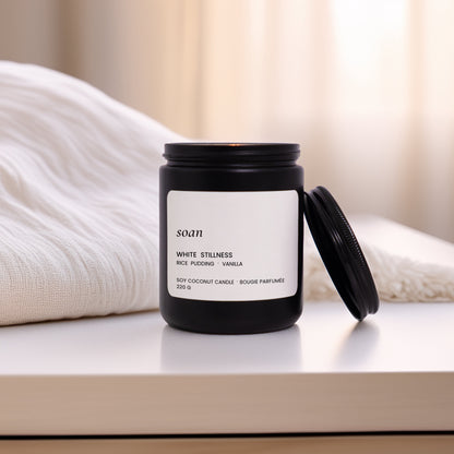 Black candle with a white label on a white surface