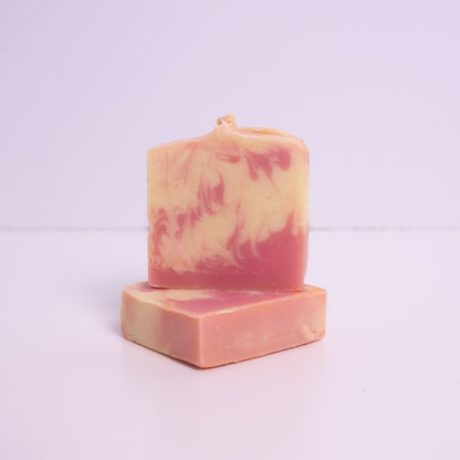 Two pink and purple artisan soap bars on a light purple background