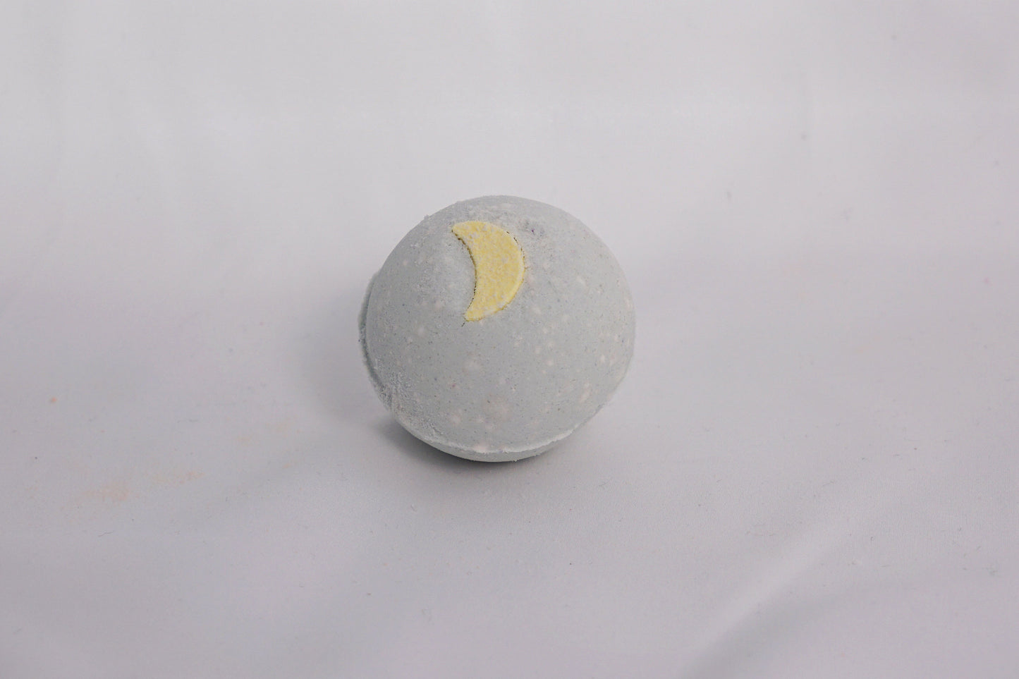 Earthy bath bomb on a neutral surface, crafted with essential oils and skin-soothing ingredients for a calming soak