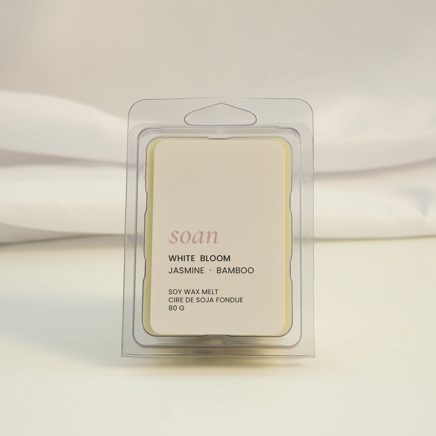 Wax melt packaging labeled 'White Bloom' on a white fabric background