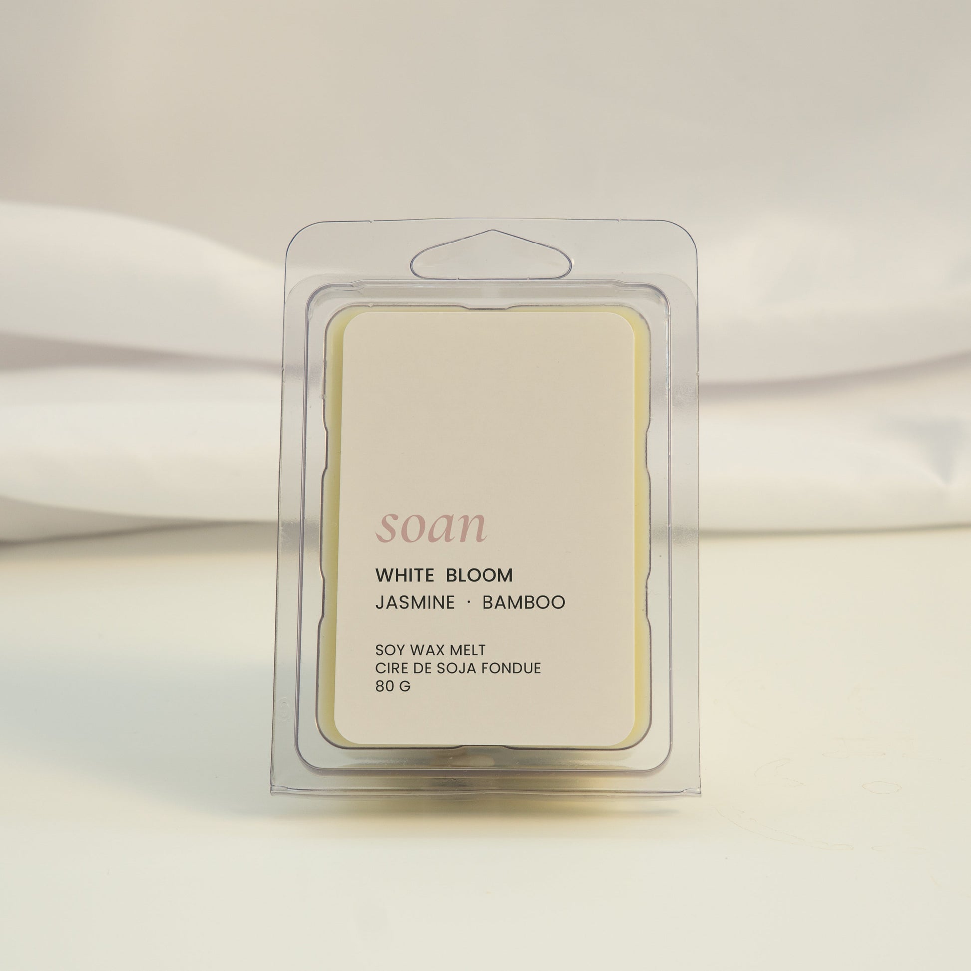 Wax melt packaging labeled 'White Bloom' on a white fabric background
