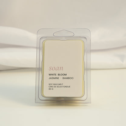 Wax melt packaging labeled 'White Bloom' on a white fabric background