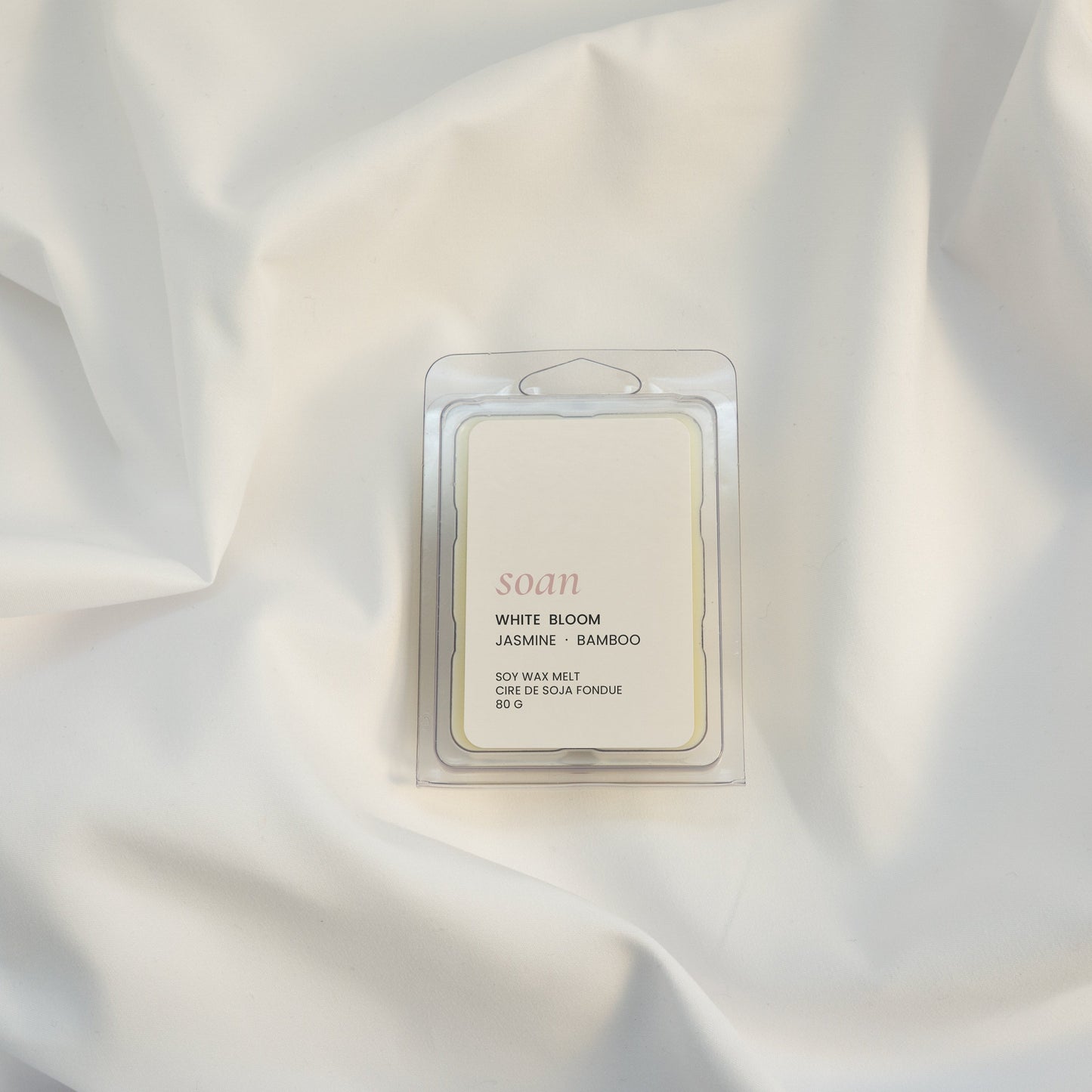 Scented wax melt packaging on a white fabric background