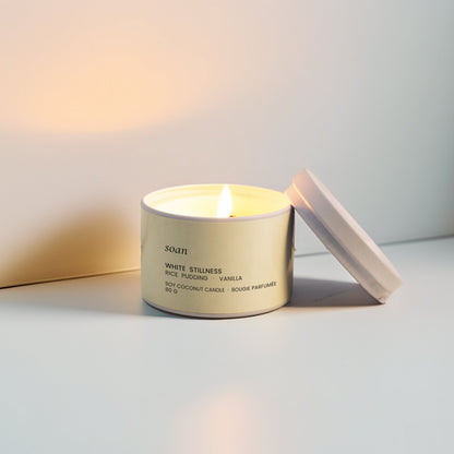 Candle in a white container with a white lid on a light surface.